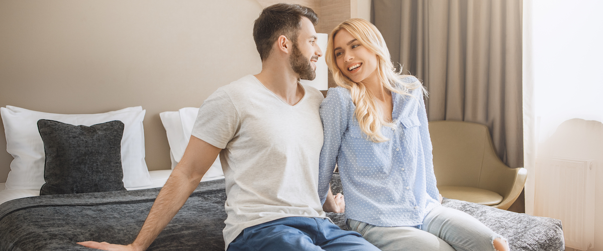 Man and woman sitting on hotel bed