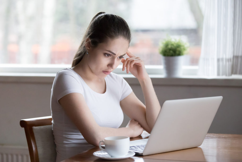 Frustrated woman looking at computer screen reading bad news