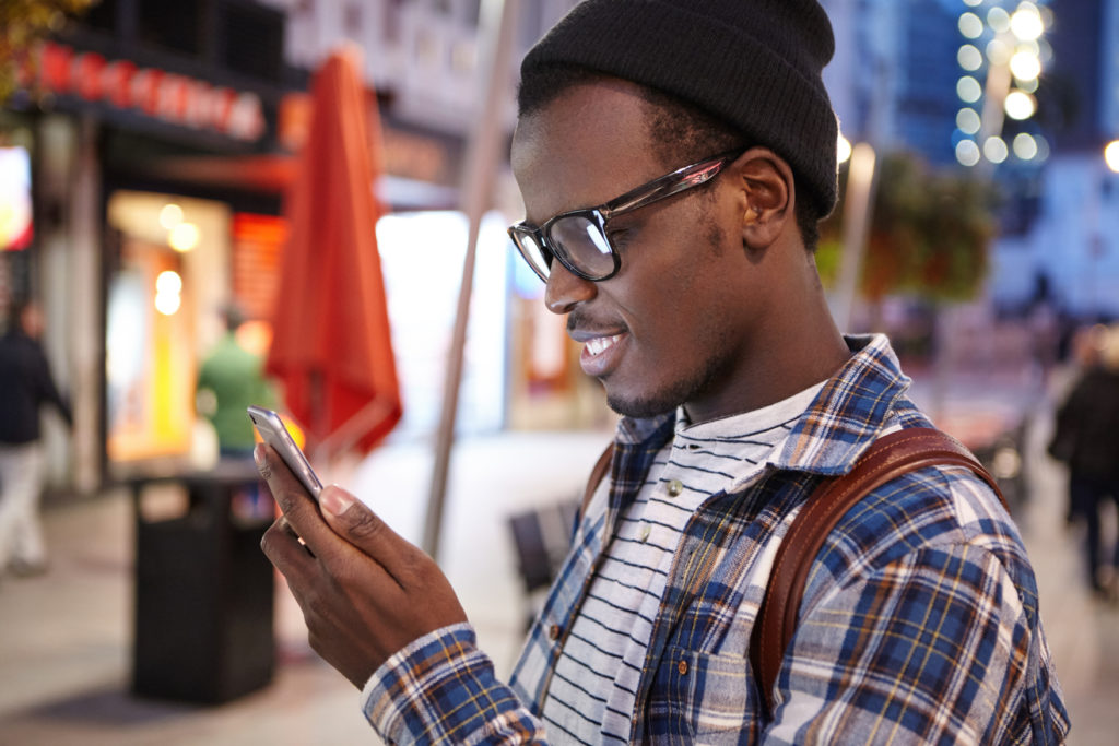 Young Man in Warm Clothes Looking at his Phone While Shopping