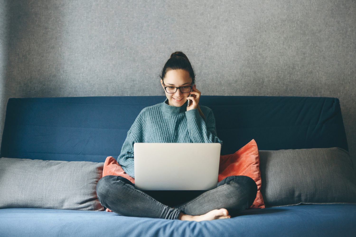 Woman Sitting on a Bed with Laptop and Phone Working from Home