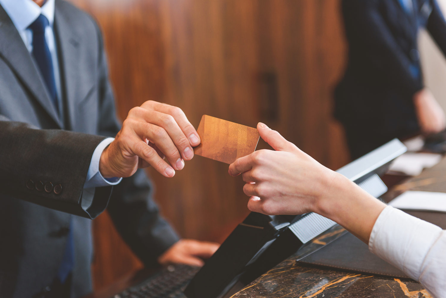 close-up image of front desk employee handing a key card to a guest