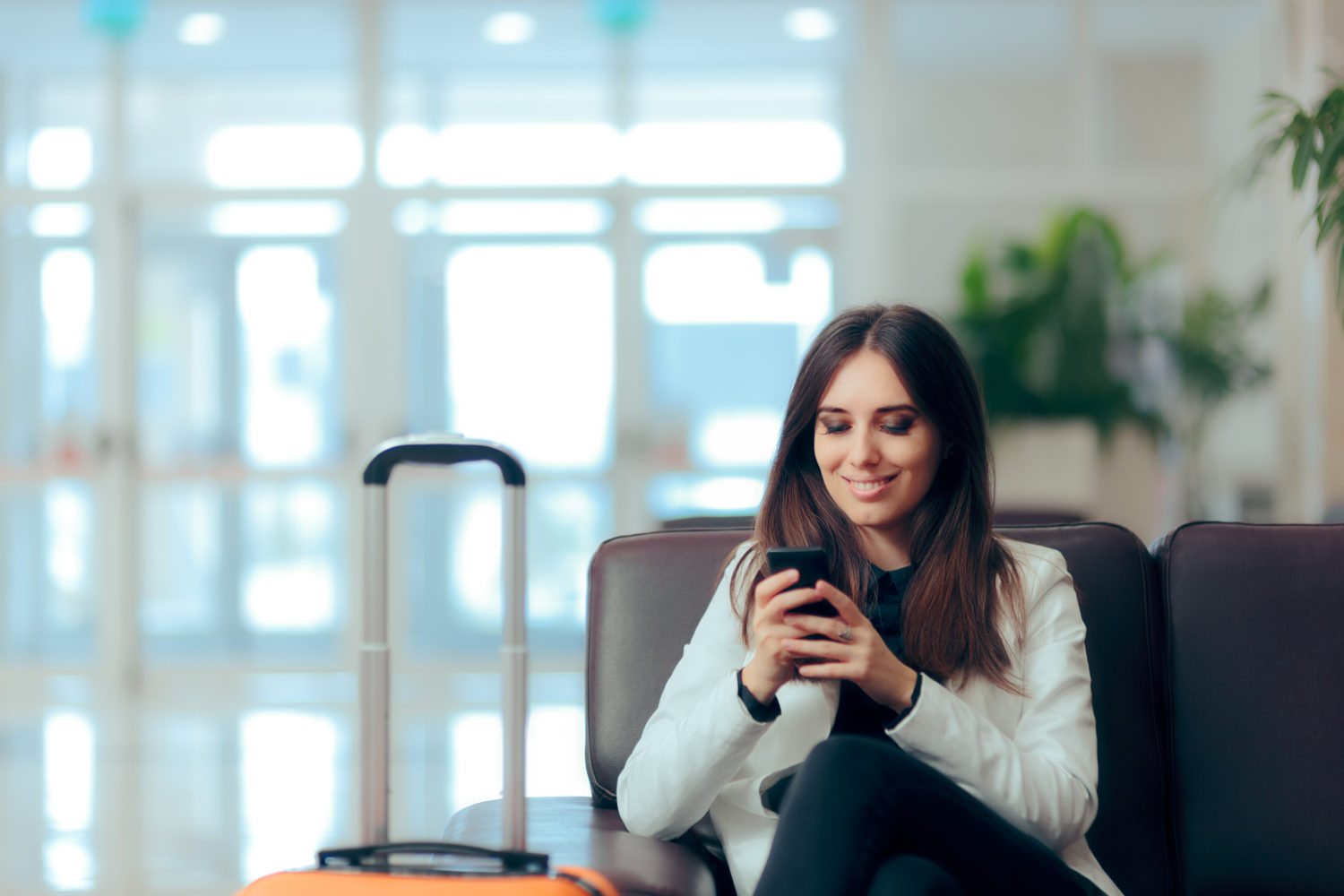 Woman sitting reading her phone in an airport terminal