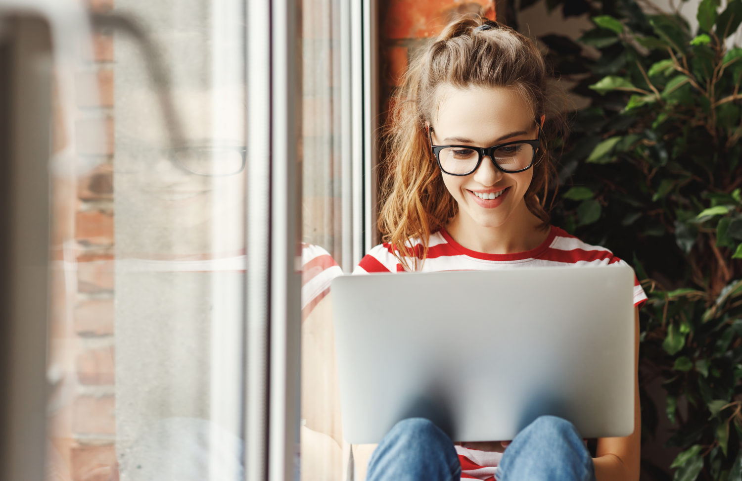 Girl sitting near a window on her computer