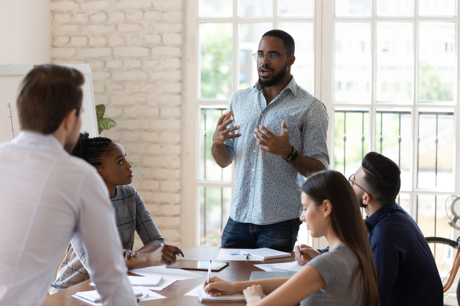 Black manager speaks to table of employees