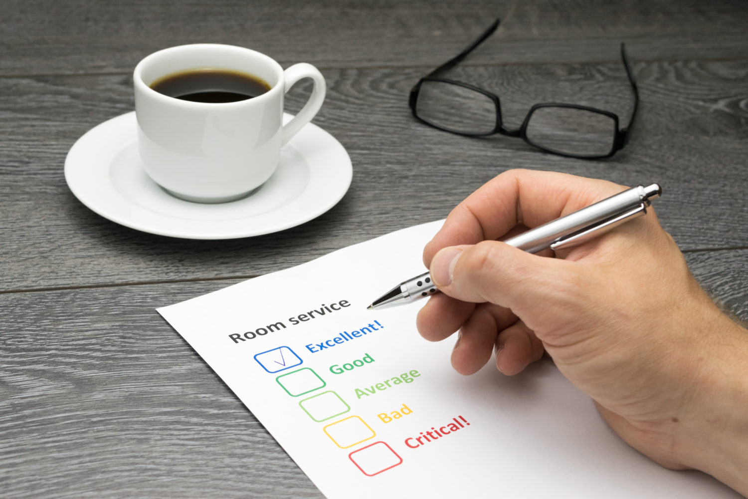 a coffee cup beside a piece of paper with room service written at the top, and a box checked with the word excellent beside it