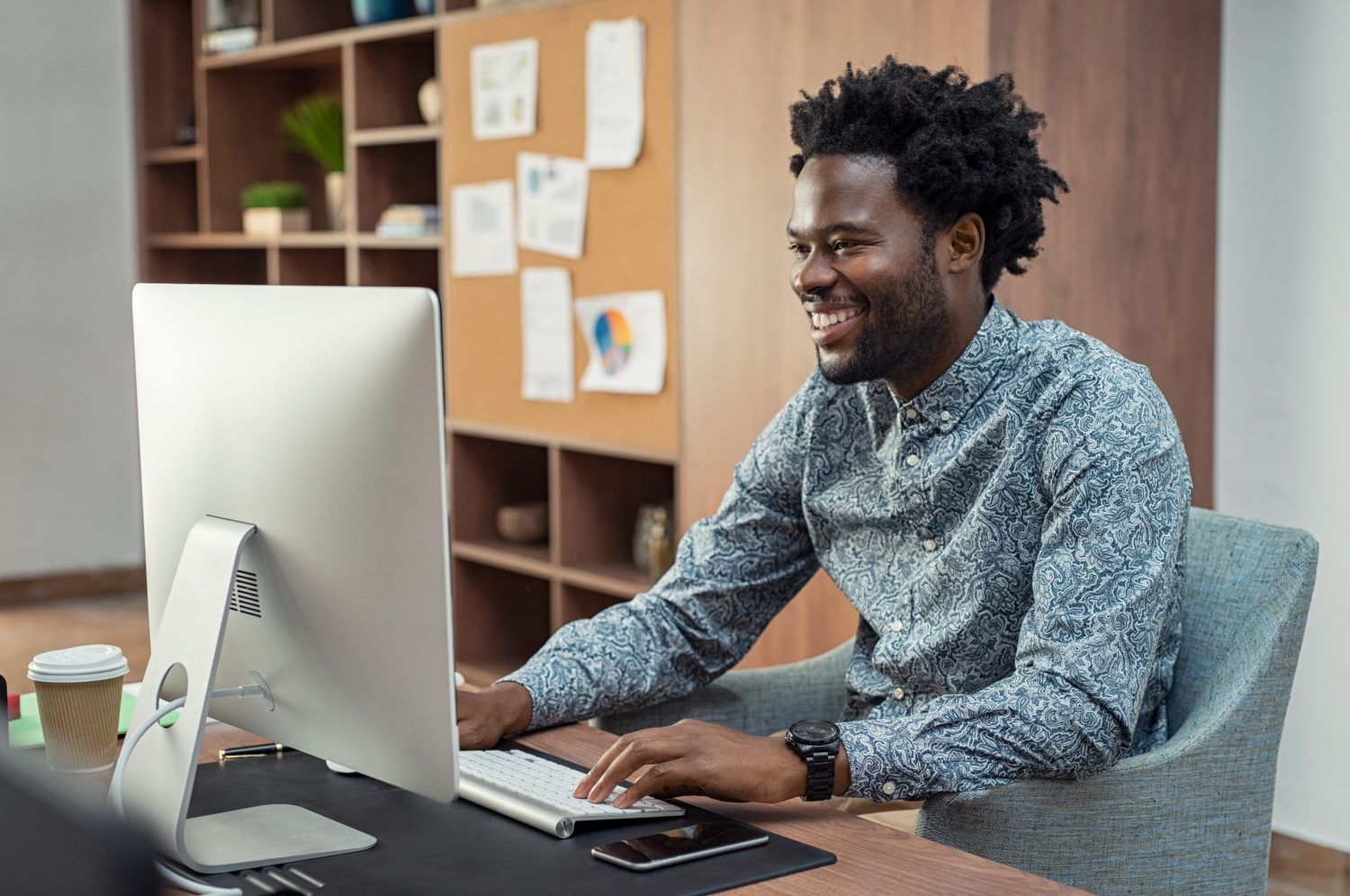 black man typing at a desk and smiling