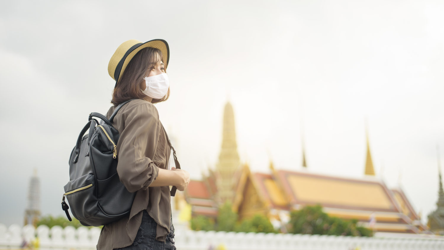 traveler wearing mask outside looking off to the right