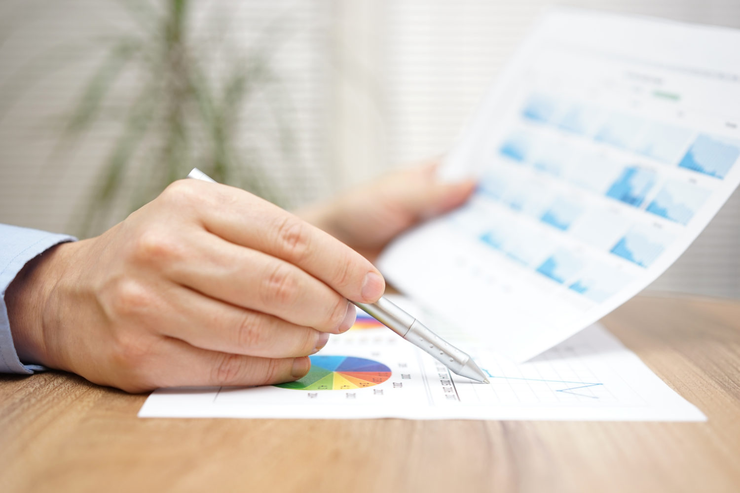 close-up of man's hand holding pen and data charts