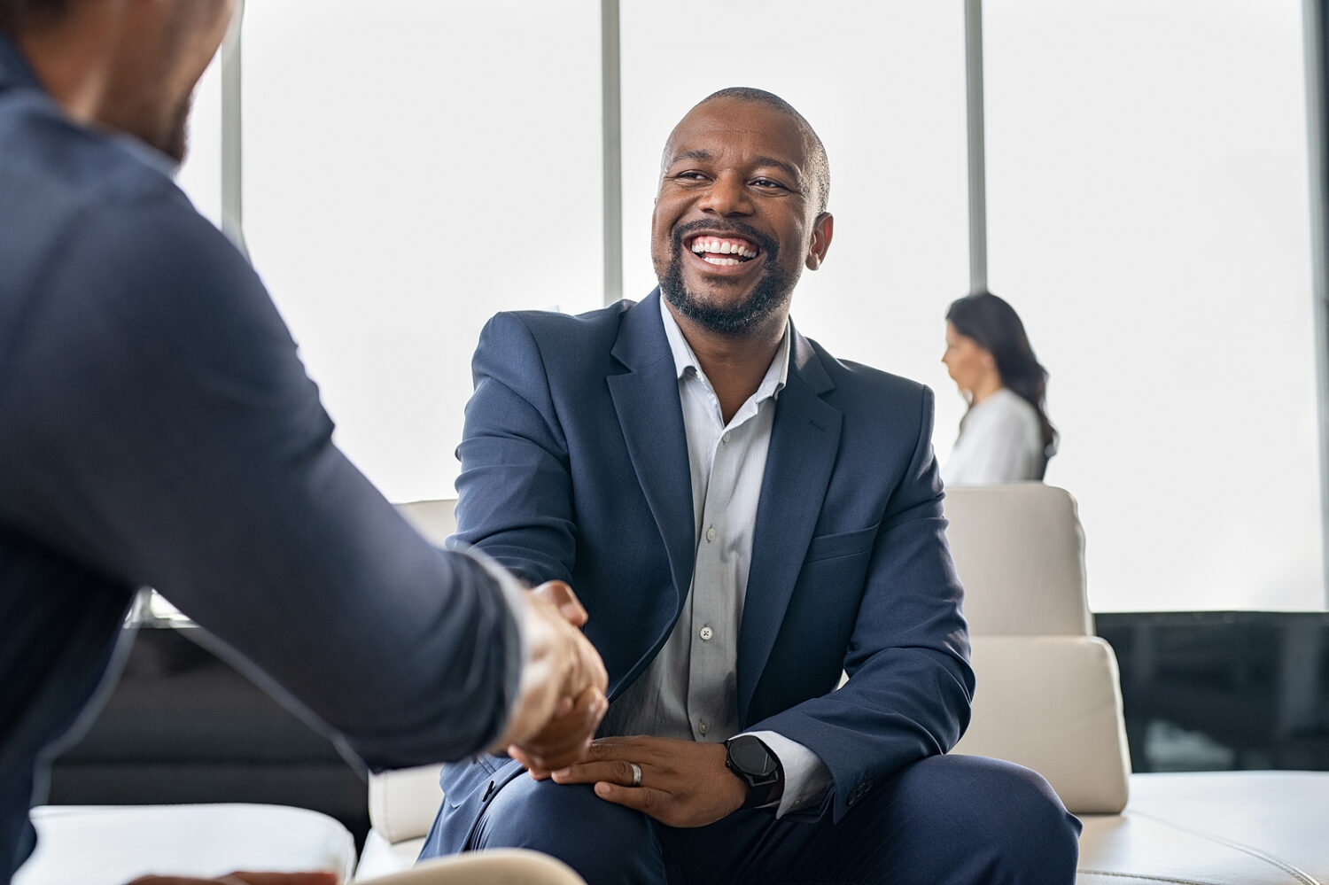 black businessman shaking hands with another man in a suit