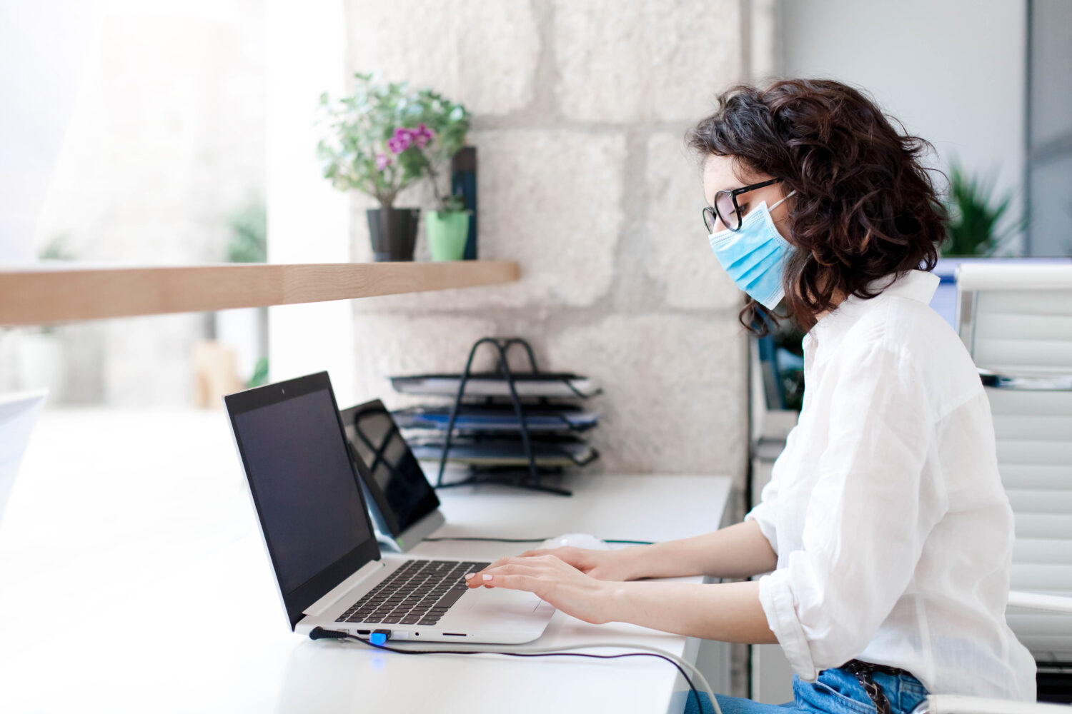 woman working at a desk wearing a face mask