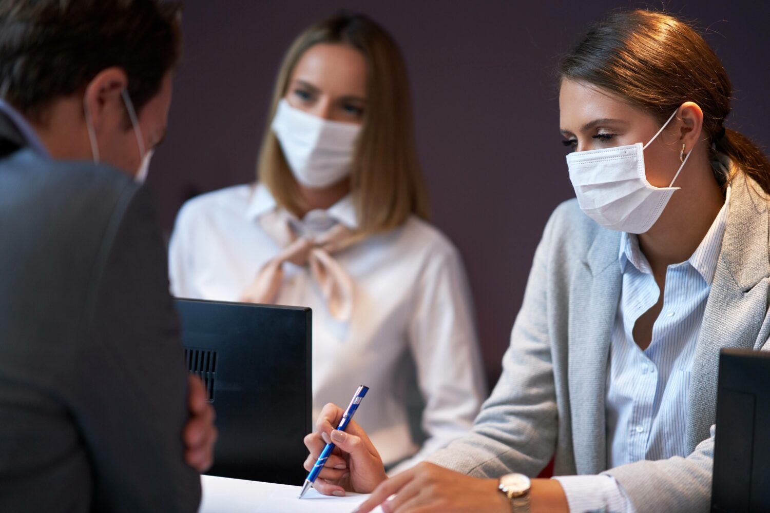 masked employees checking in masked guest at a hotel