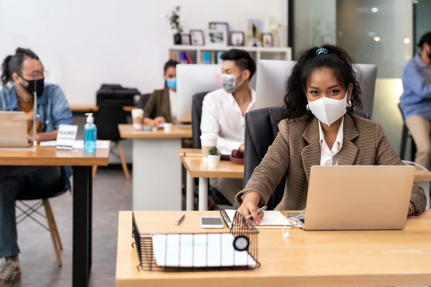 team members working distanced and masked in an office at laptops