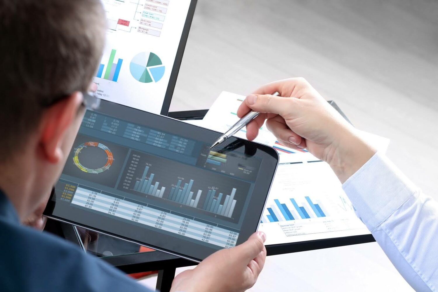 businessmen reviewing a tablet with graphs and charts on the screen