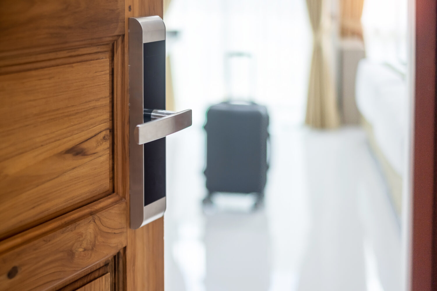 hotel door open to reveal a suitcase inside the room