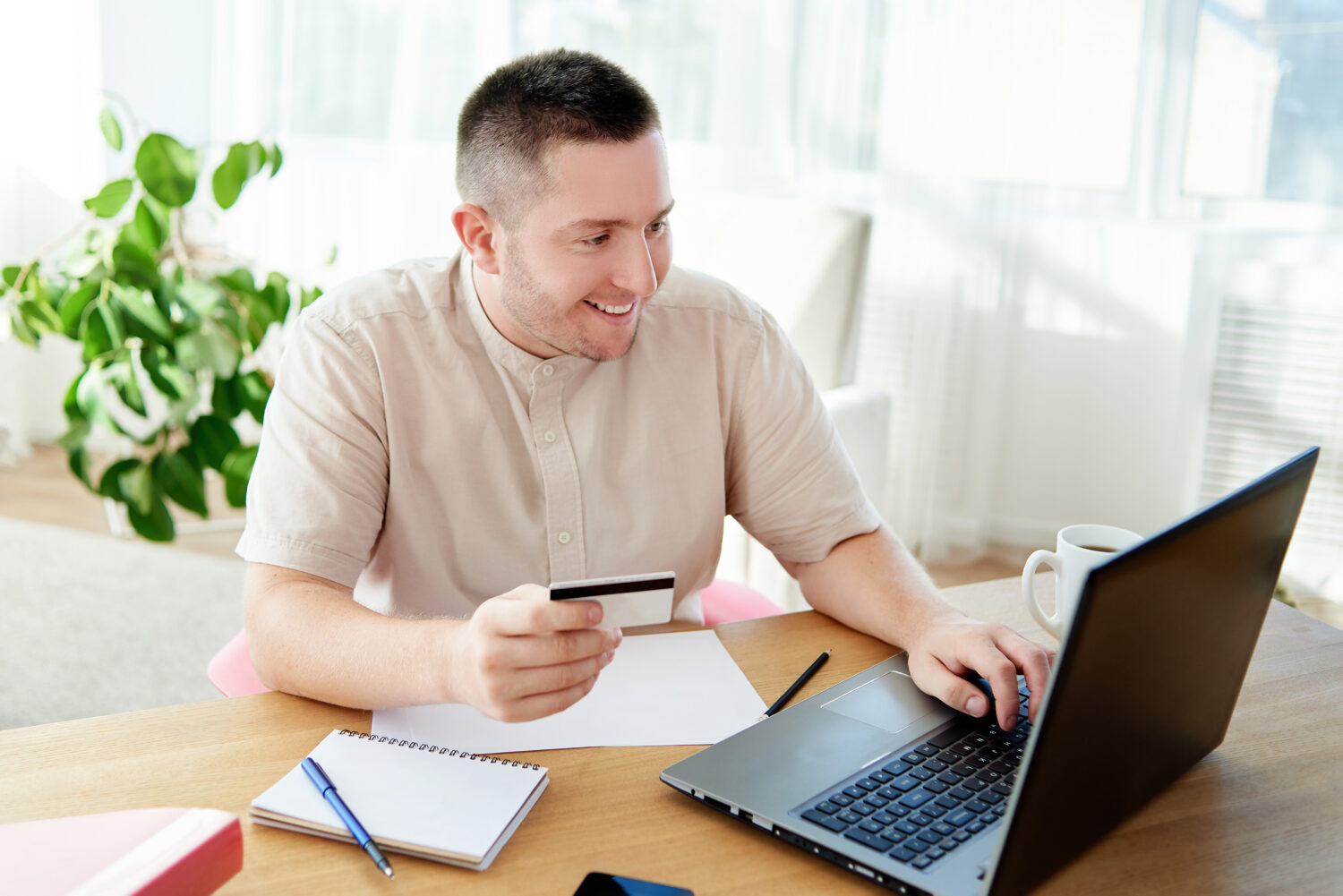 man looking at his laptop holding a credit card