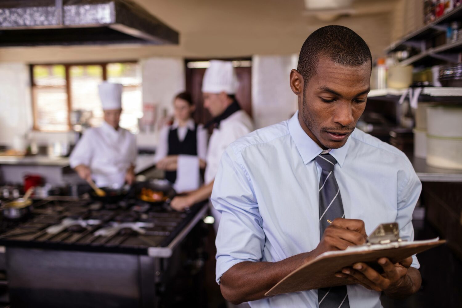 male restaurant manager writing on a clipboard