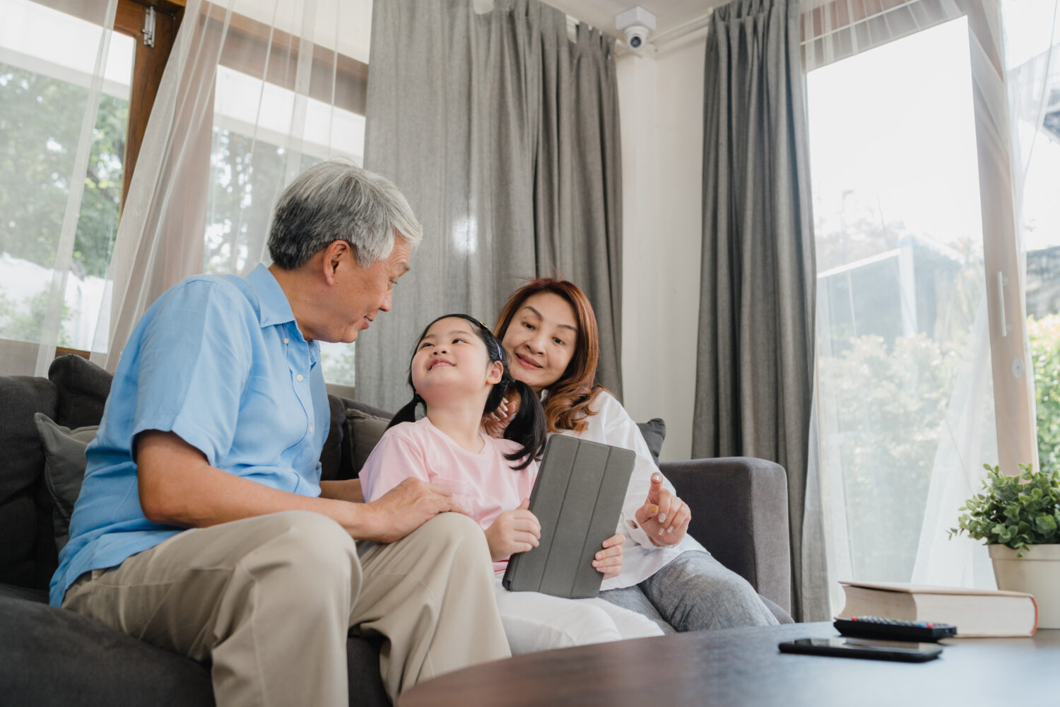 asian grandparents browsing social media with their young granddaughter