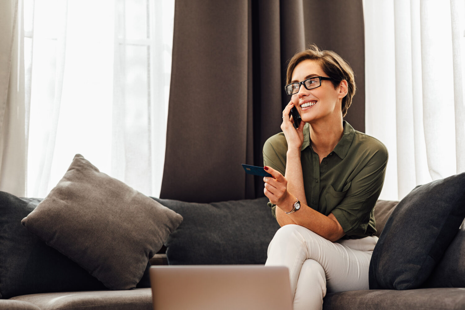 woman with short brown hair speaking on her phone in a hotel room