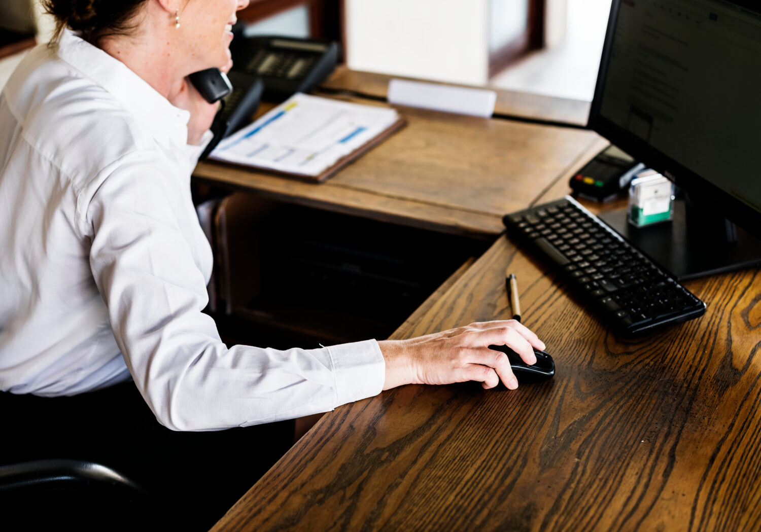 woman using a computer and on the phone at a reception desk