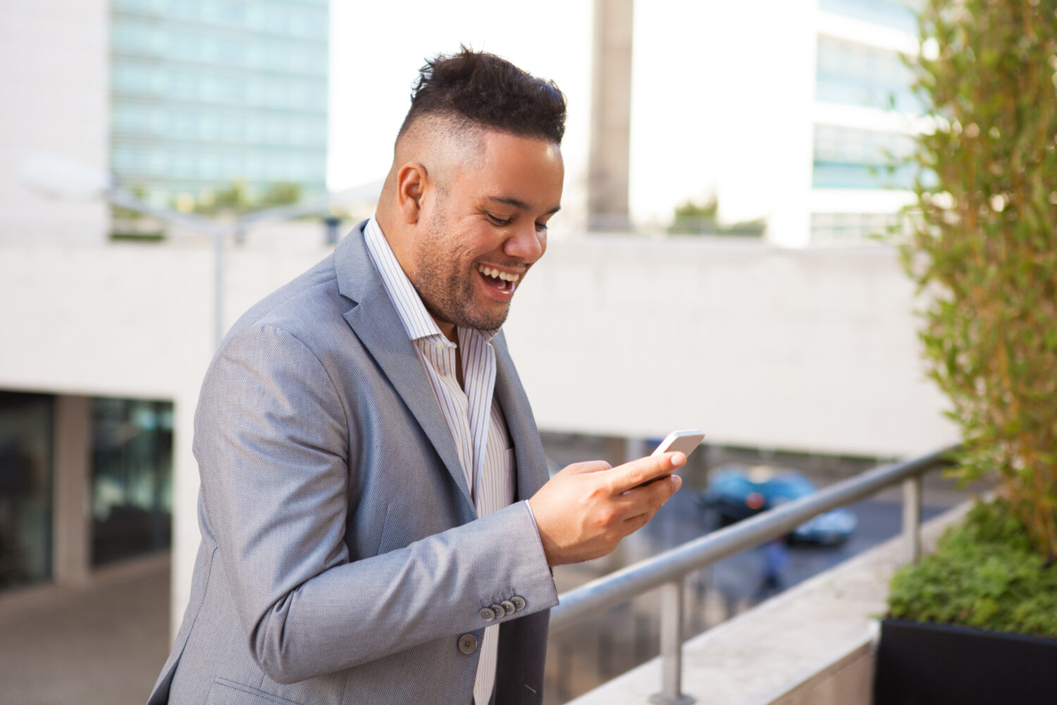 happy hispanic man smiles at his phone while walking up stairs