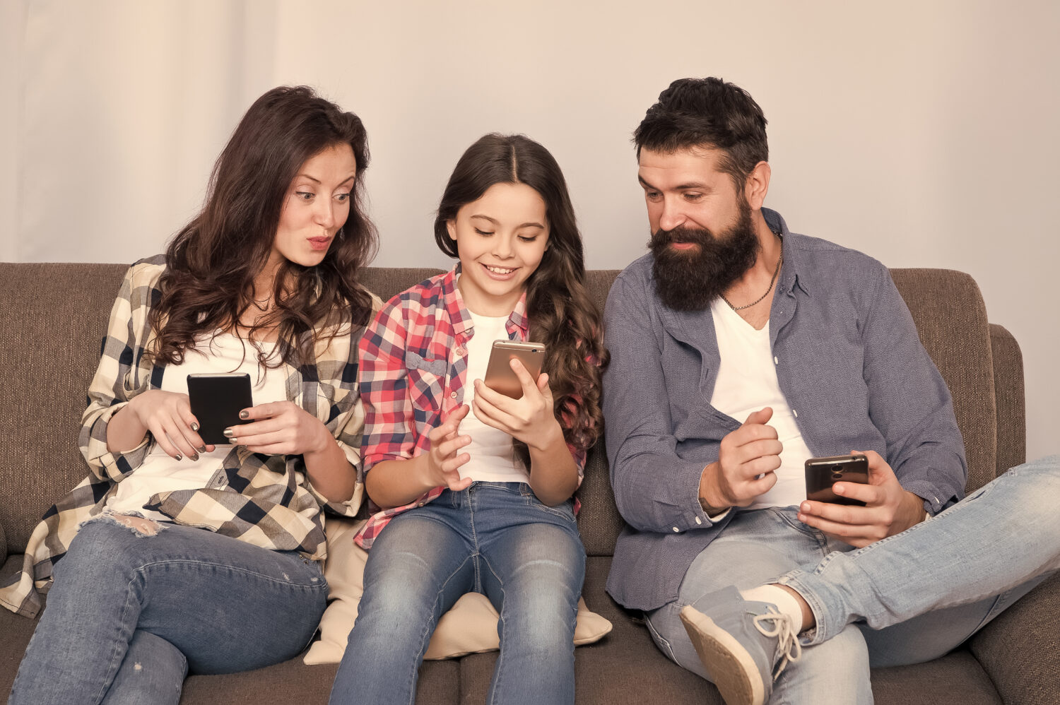 mother and father look over a daughter's shoulder to read what is on her phone