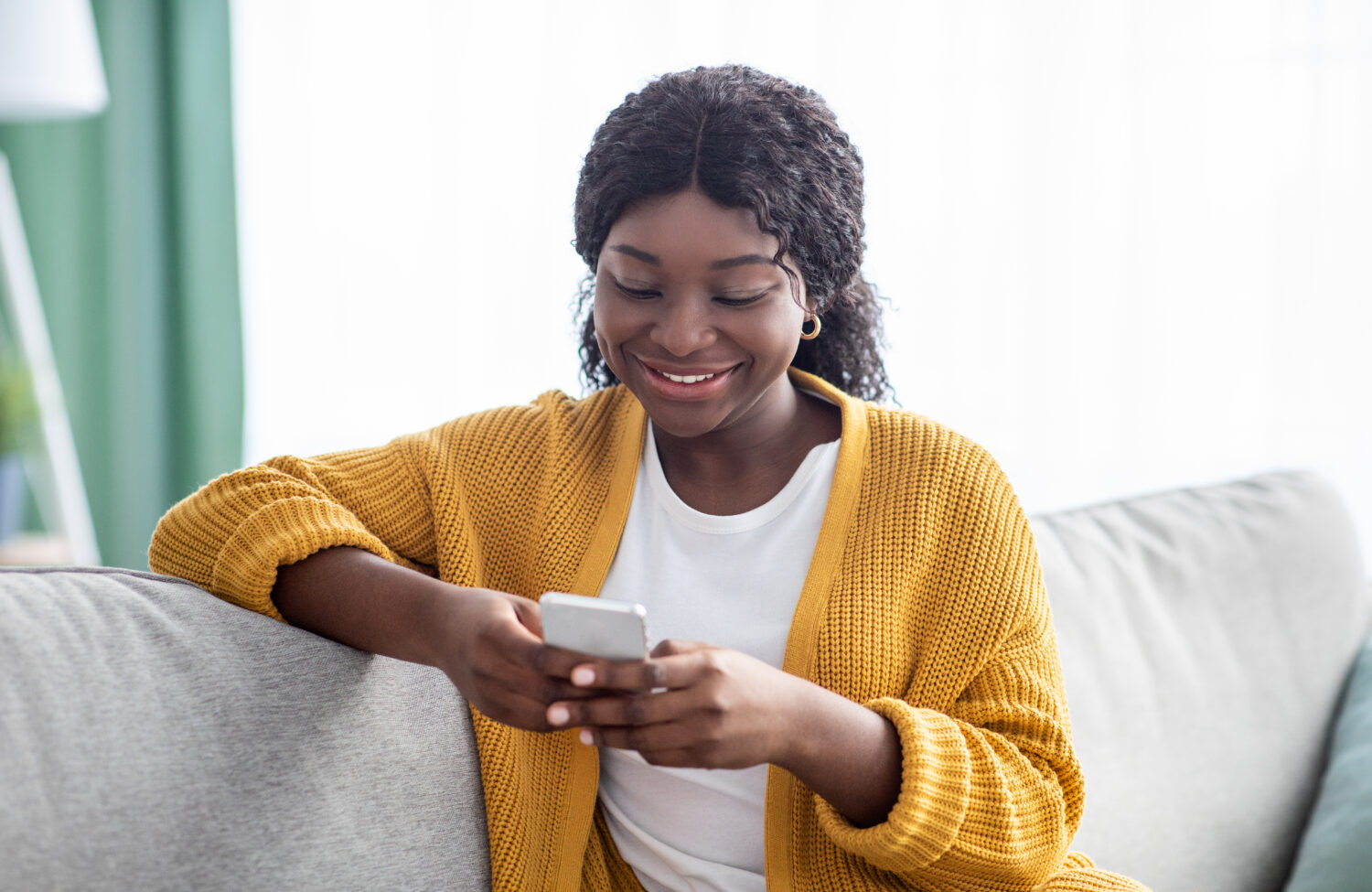 african american woman smiling and using her phone
