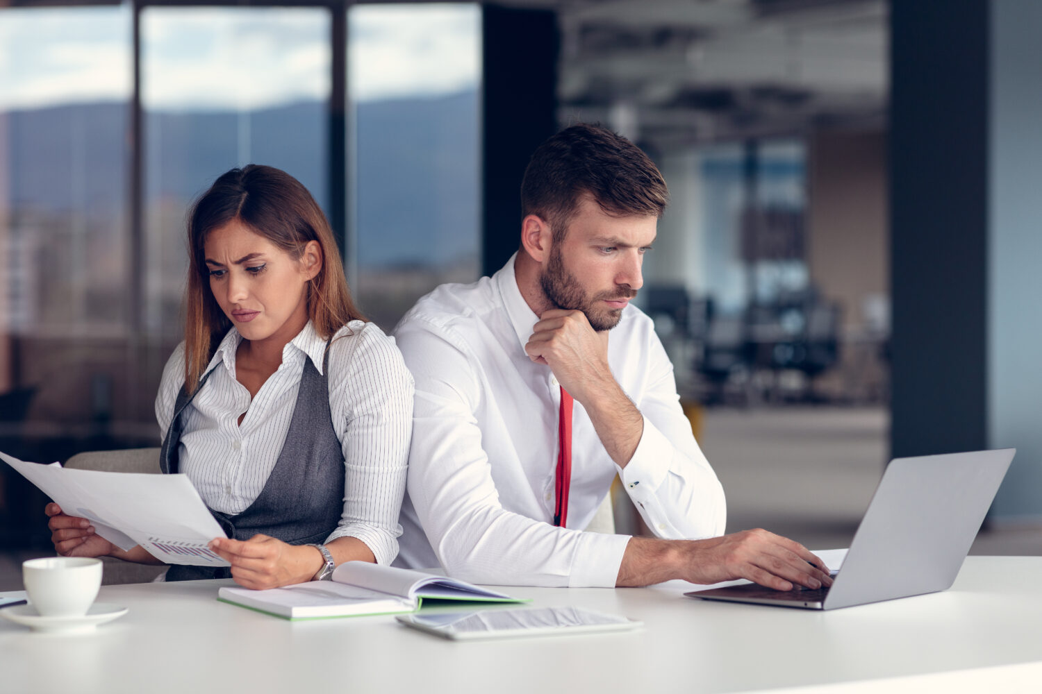 businessman and businesswoman sitting at a table facing away from each other