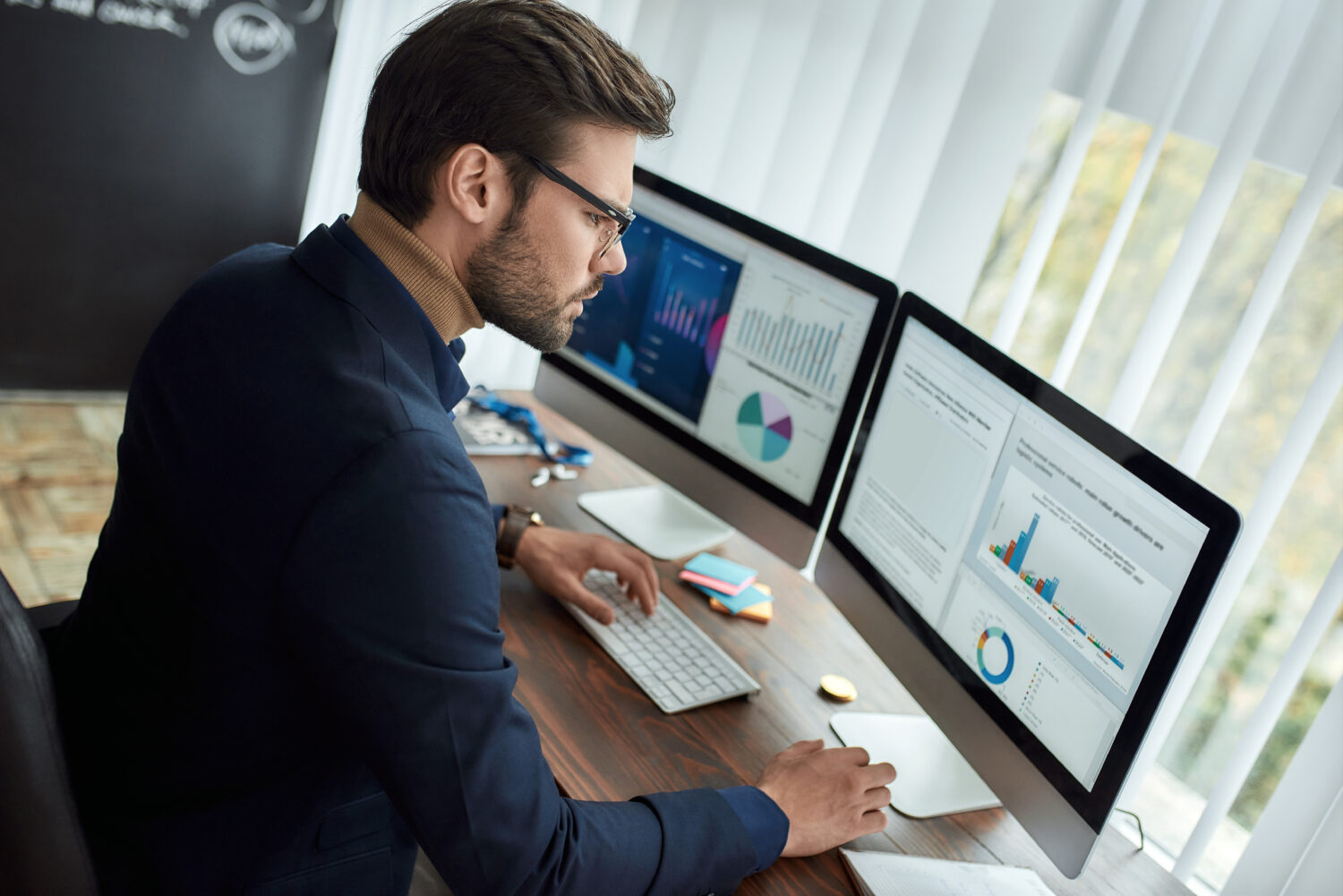 businessman analyzing data displayed on two monitors