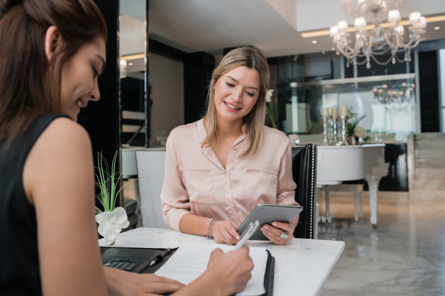 two women fill out paperwork at a table together