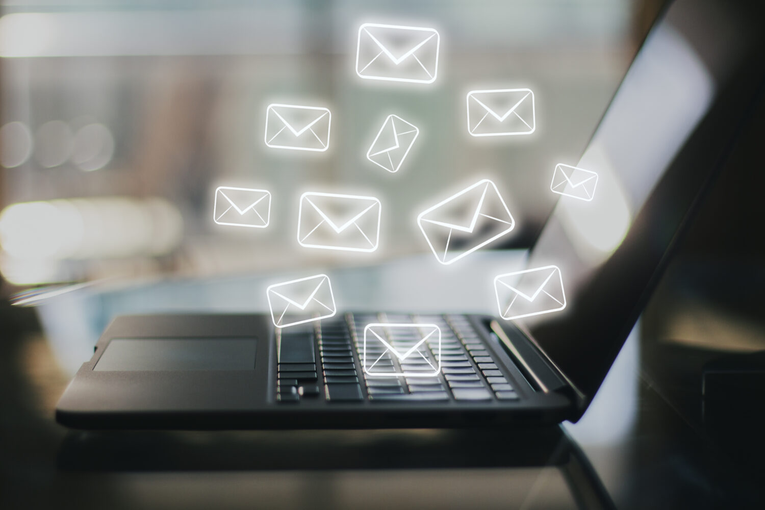 open laptop on desk with email icons sketched in the space above the keyboard