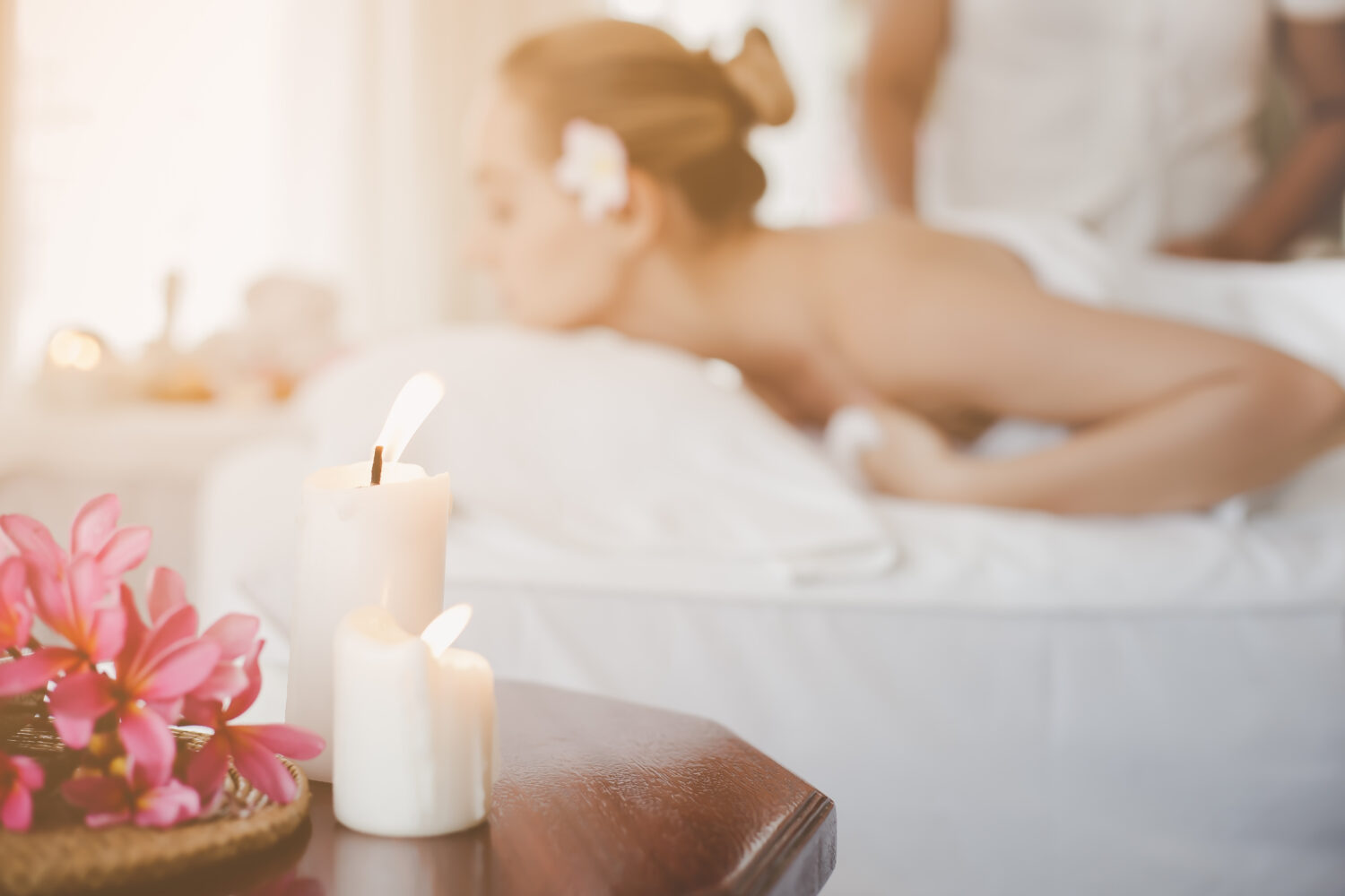 foreground candles on a table and a woman getting a massage in the background