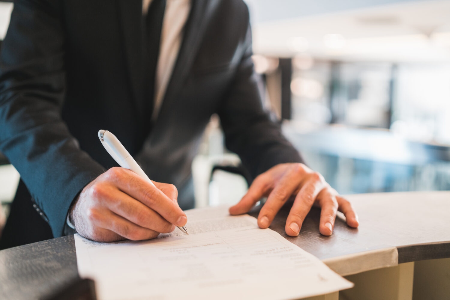 cropped image of businessman writing on papers at the front desk