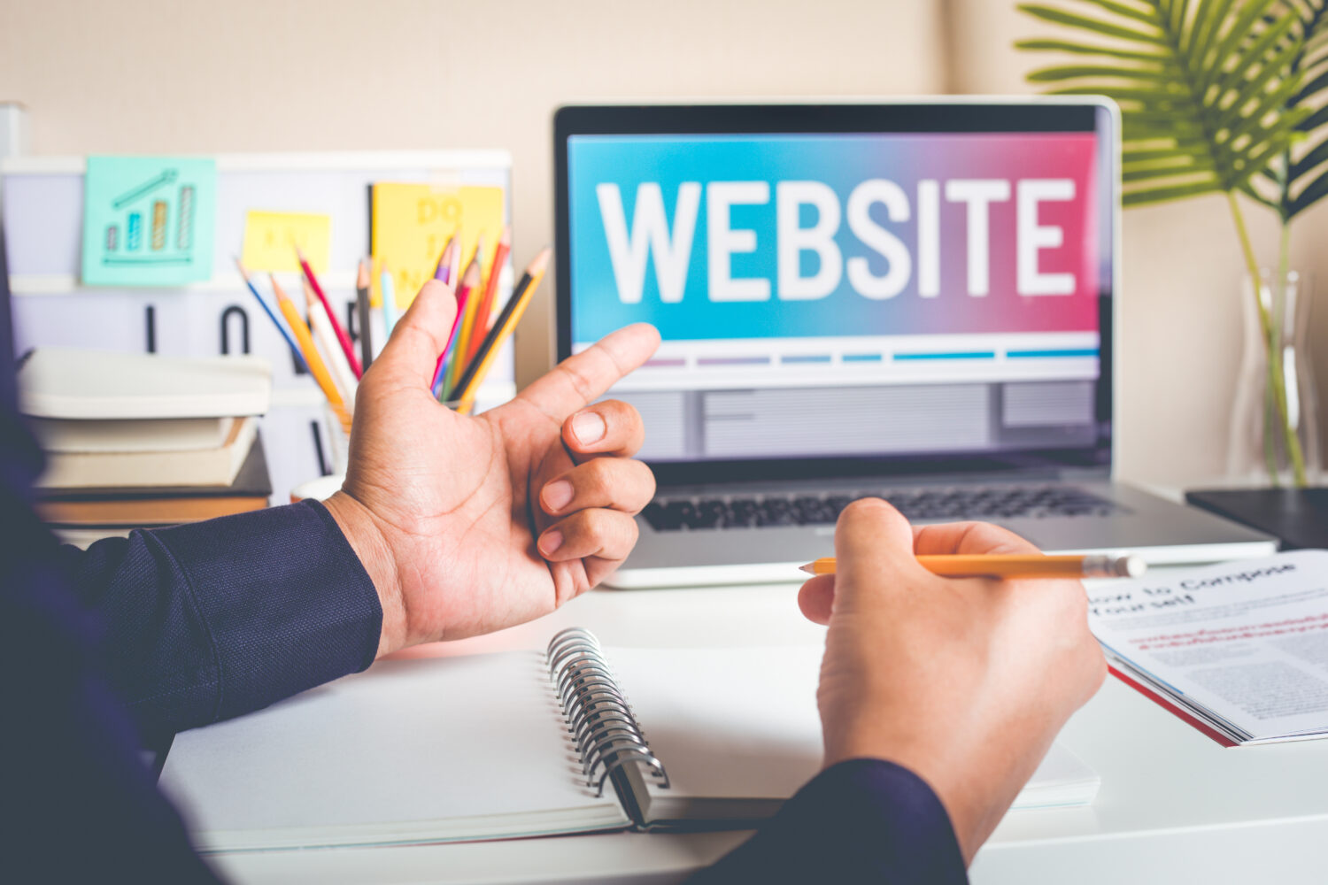 a close cropped photo of hands gesturing to a laptop with the word "website" written on it