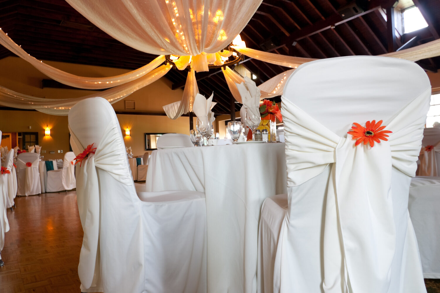 wideangle of a wedding venue focus on a single table with white covered chairs